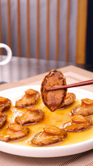 Dried Abalone and Sea Cucumber in Golden Sauce - Premium Asian Seafood Delicacy on White Plate