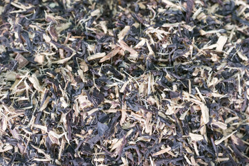 Fototapeta premium Dried herbal mixture with dark leaves and wood shavings in a close up view on a flat surface