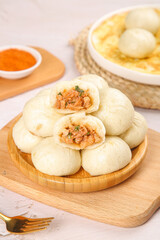 Steamed Chinese Bao Dumplings with Savory Filling on Wooden Bamboo Plate - Traditional Asian Dim Sum Cuisine