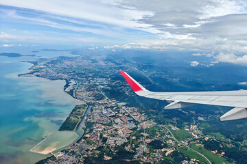 Aerial view from an airplane window showing the cityscape, coastline, and mountains of Kota Kinabalu, Sabah, Malaysia.