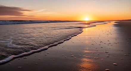 Sunset over the ocean with gentle waves lapping on the sandy shore