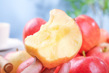 Heart-shaped bitten red Fuji apple from Xinjiang Aksu region held in hand with fresh apples in background