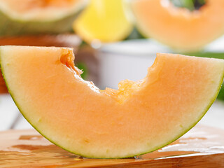 Fresh Cantaloupe Melon Slice with Bite Mark on Wooden Board