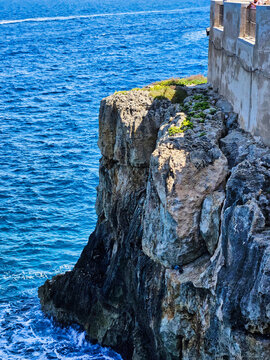 A rugged cliffside with waves crashing against the rocks far below. Rochedo sobre o mar. Island in the blue sea. Kornati islands. Natural pool in the mountain rocks coast. The sea and mountains.