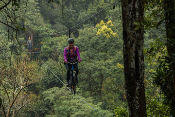 Fototapeta premium Woman riding sky bike on cable in tropical rainforest