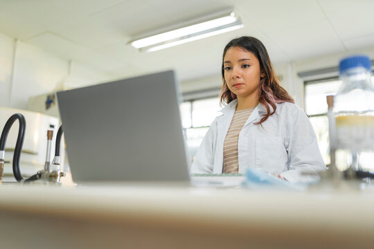 Young female scientist working on laptop in laboratory