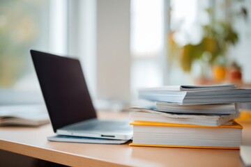 Workspace with Laptop and Stacked Books on Desk near Window Offering a Bright Ambiance
