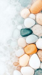 Obraz premium Smooth pebbles lying on a light sandy surface, showing different colors and textures, creating a natural border on a background.