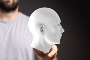 Conceptual image: man holding a white head model, representing AI, mind, intellect, and future technology.