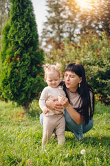 Fototapeta premium A mother tenderly hugging her little daughter, who holds a beautiful flower