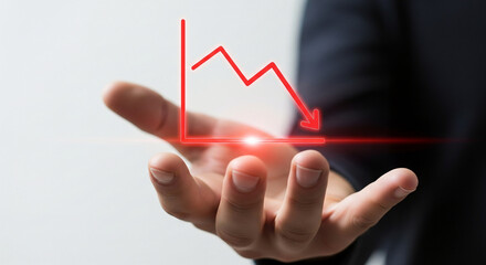 Concept of economic recession and business crisis with a businessman holding a virtual projection of a falling red graph line indicating financial loss