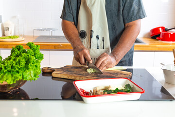Man Cooking in Kitchen Cutting Vegetables on Wooden Board