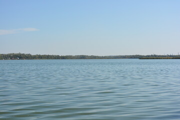 Beautiful, bright nature, landscape near the Samara River, Ukraine. Deep blue river with small waves against the background of a green bank with trees and beautiful new houses.