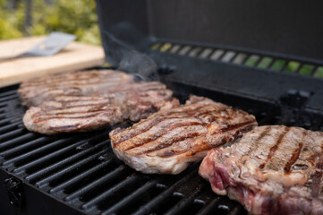 Juicy grilled steaks sizzling on an outdoor barbecue grill
