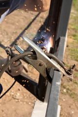 Close-up of welding process with sparks and metal clamps outdoors. National Welding Month
