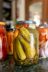 Assorted jarred preserves on kitchen counter with pickles and vegetables. National Pickle Day