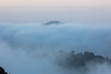 Burgruine Meistersel über einem Nebelmeer mit Hügeln im warmen Licht der ersten Sonnenstrahlen