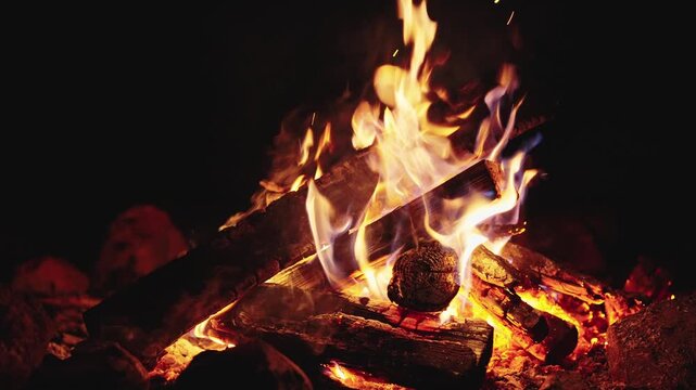 Seamless slow motion video of a cozy campfire at night with glowing logs and dancing flames. Perfect for digital fireplace, meditation background, and relaxing screens. Loopable fire background.