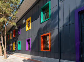 Contemporary building facade with square windows in vibrant frames of orange, yellow, green, and purple, urban architectural detail.