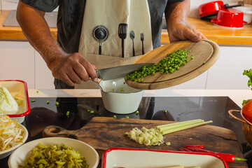 Man Pouring Chopped Long Beans into Bowl in Kitchen