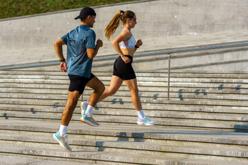 Couple jogs up stone steps outside for exercise and fitness