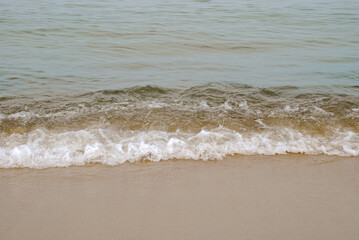 Serene ocean waves gently reaching sandy shoreline at tranquil beachfront