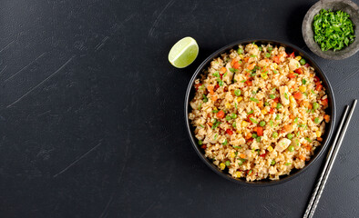 Fried rice with chicken,vegetables:carrots,peppers,corn and green peas on black background. Top view