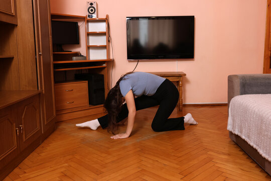 Woman bends forward in lunge, stretching for flexibility and muscle development at home.