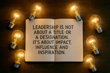 Open notebook with quote about leadership surrounded by illuminated light bulbs on a wooden surface inspiration