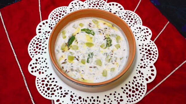 Lauki raita topped with jeera and chilli tadka in a yellow bowl on white round tray. vrat, upwas or fasting food.