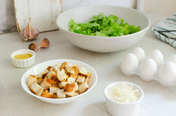 The process of cooking traditional Caesar salad with croutons and parmesan cheese on a gray table. The concept of traditional American cuisine. Horizontal orientation. Selective focus.