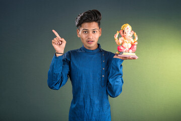 Happy young man holding and posing with Ganesha statue on the occasion of Ganesh Festival