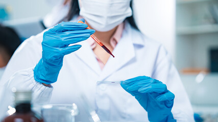 Female scientist in protective gear handling a blood sample in a laboratory, representing virus...