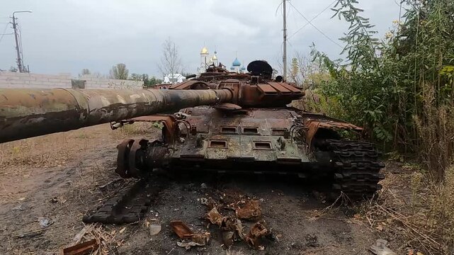 Destroyed Russian T-72 tank hit by Ukrainian forces. Autumn gloomy day, church in the background. Powerful footage showing war reality, strength, sacrifice, and courage