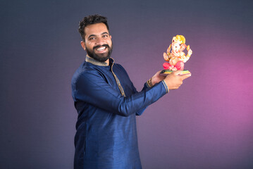 Happy young man holding and posing with Ganesha statue on the occasion of Ganesh Festival