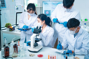 Group of scientists collaborating in a laboratory, engaging in teamwork and planning around...