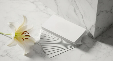 Elegant white lily flower with a stack of blank business cards on a marble background perfect for branding and stationery mockups