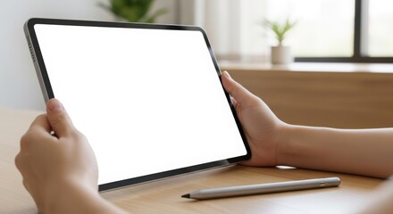 Hands holding tablet with blank screen and stylus pen showcasing modern technology perfect for website and app mockups