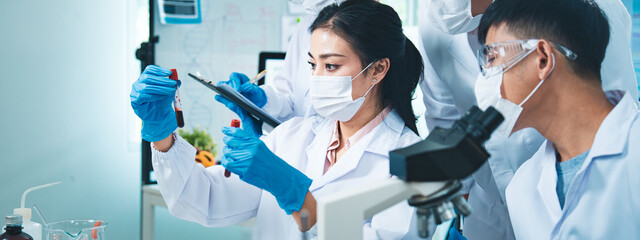 A group of scientists helping each other in the laboratory, working together to find answers about diseases, DNA, and mysterious substances, symbolizing teamwork and discovery.