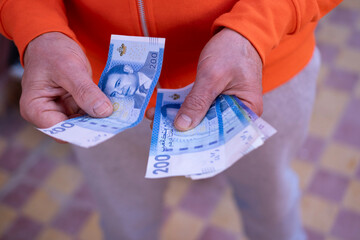 closeup male hands hold Moroccan dirham money, count paper dirham banknotes, concept cash payments,...