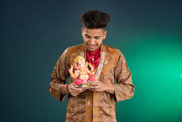 Happy young man holding and posing with Ganesha statue on the occasion of Ganesh Festival
