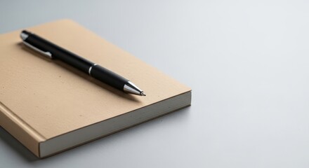 Naklejka premium Minimalistic Writing Setup with Pen and Brown Notebook on Light Background for Creative Inspiration