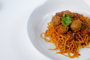 Spaghetti meatballs on a white plate with a white background