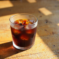 Refreshing Iced Coffee on a Wooden Table Bathed in Sunlight