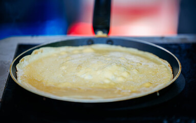 Golden crepe cooking in pan on stovetop at kitchen