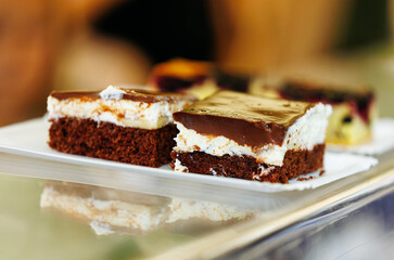 Chocolate cream cake slices on a plate with glazed topping and reflective surface