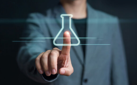 Businessman's hand touching virtual holographic laboratory flask icon, symbolizing scientific research, chemical innovation, and experimental solutions.
