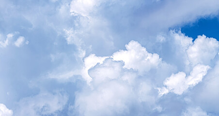 Fluffy cumulus clouds drift across a serene blue sky, evoking calm and fair weather.