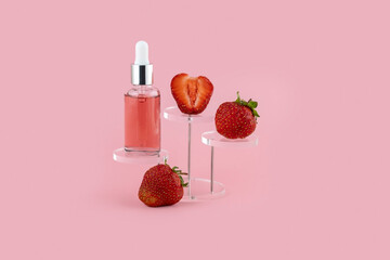 Dropper bottle and strawberries on a pink background. Presentation of skin care products.