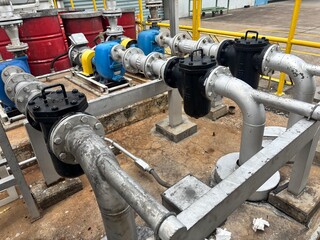 Industrial pumping station featuring multiple pumps, motors, and a complex network of pipes. The...